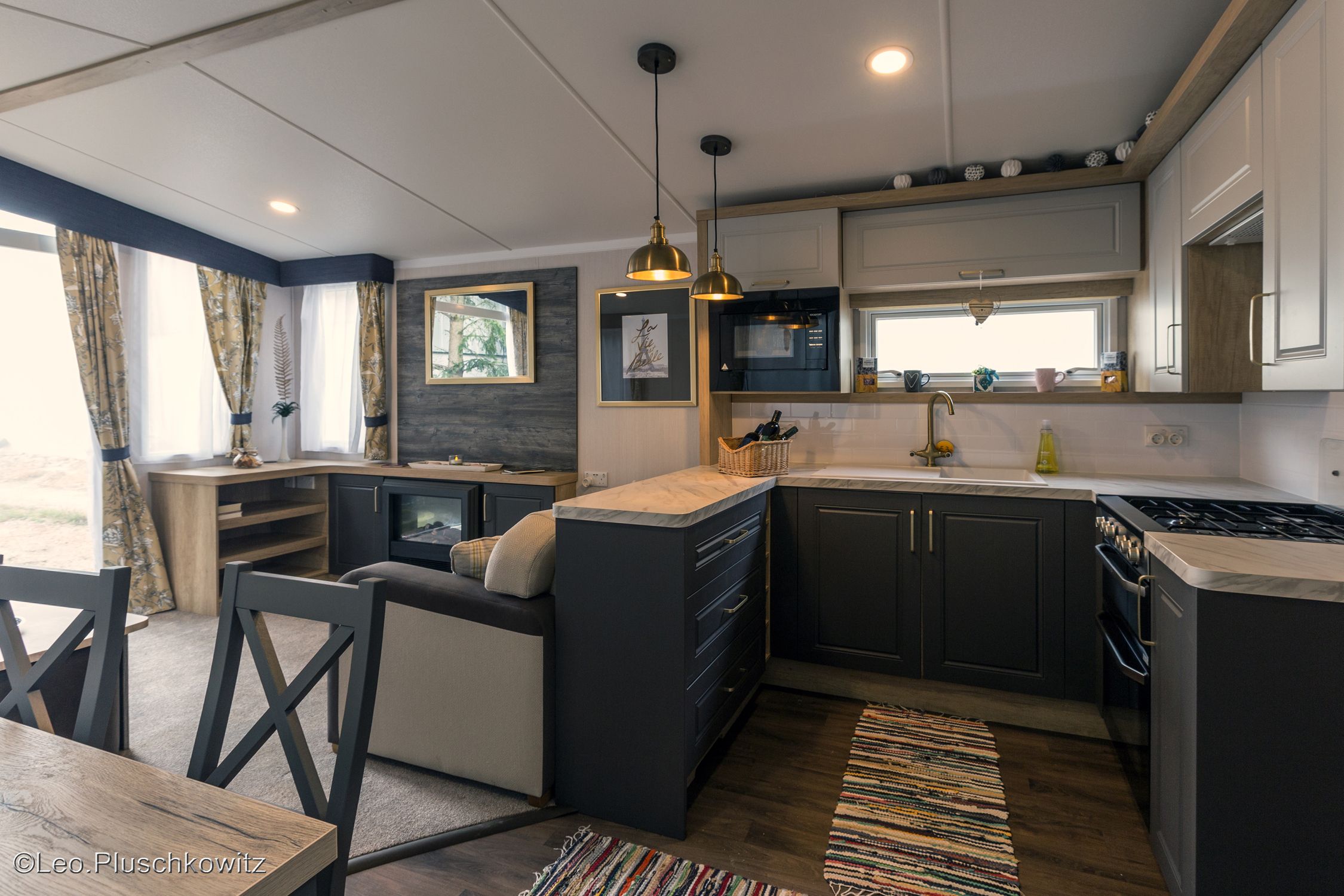 Moderne Küche mit dunklen Schränken, Herd, Spüle und Hängelampen.