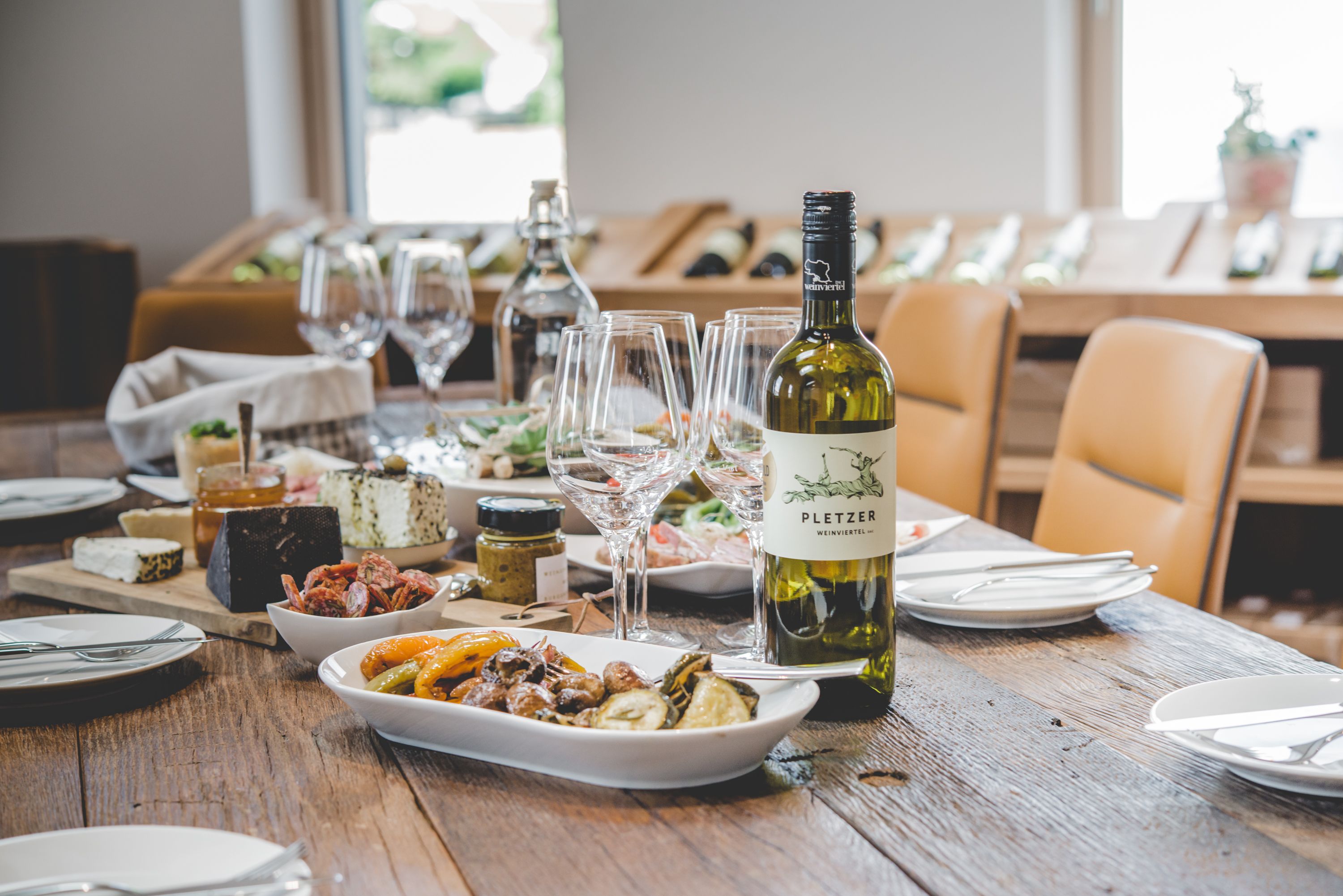 Ein gedeckter Tisch mit Weinflasche, Gläsern und verschiedenen Speisen.