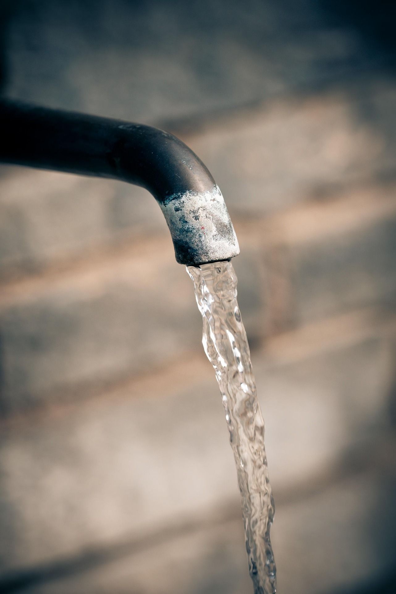Close-up of a tap with flowing water against a blurred background.