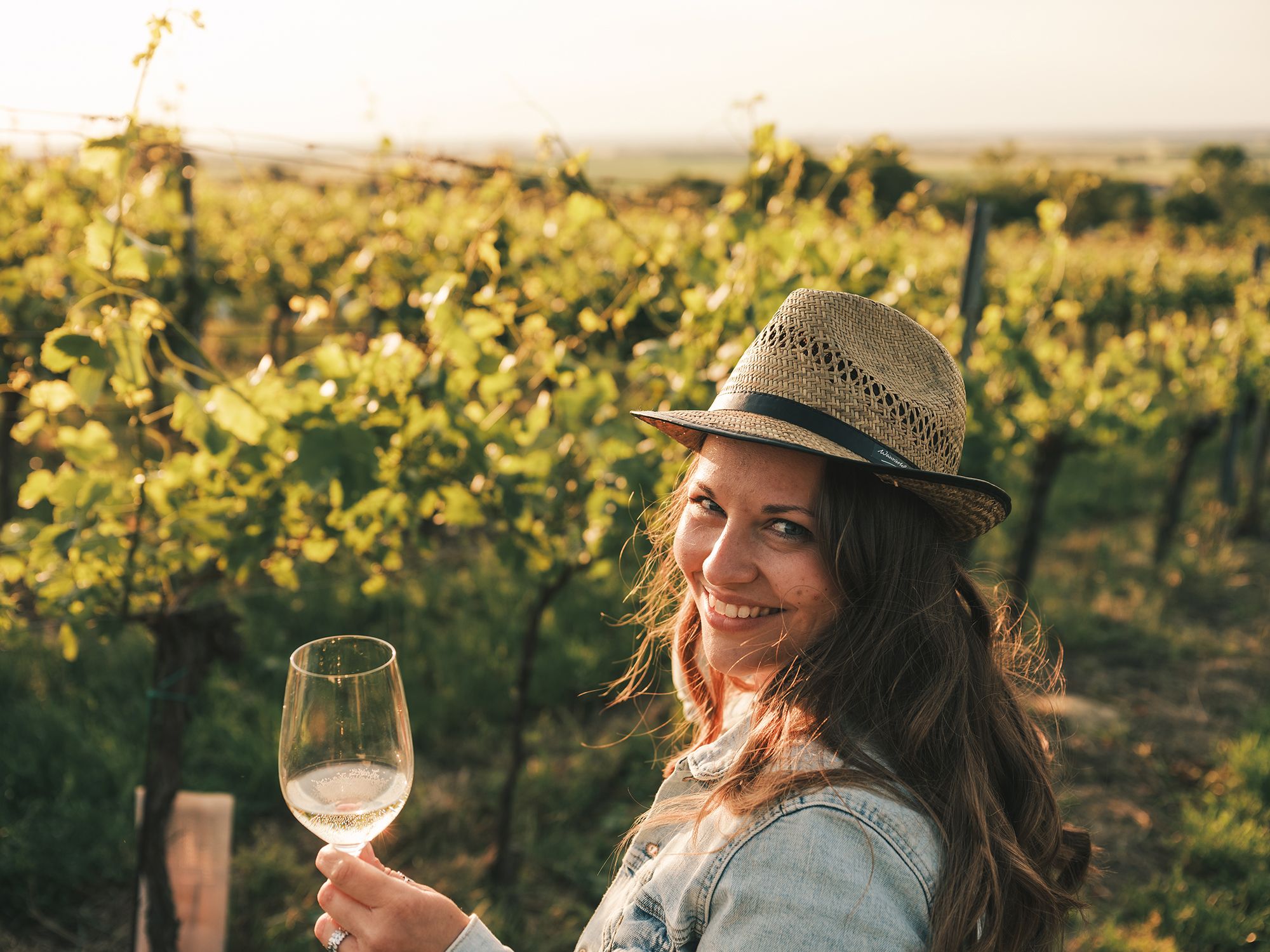Eine junge Frau hält ein Glas Wein in der Hand.