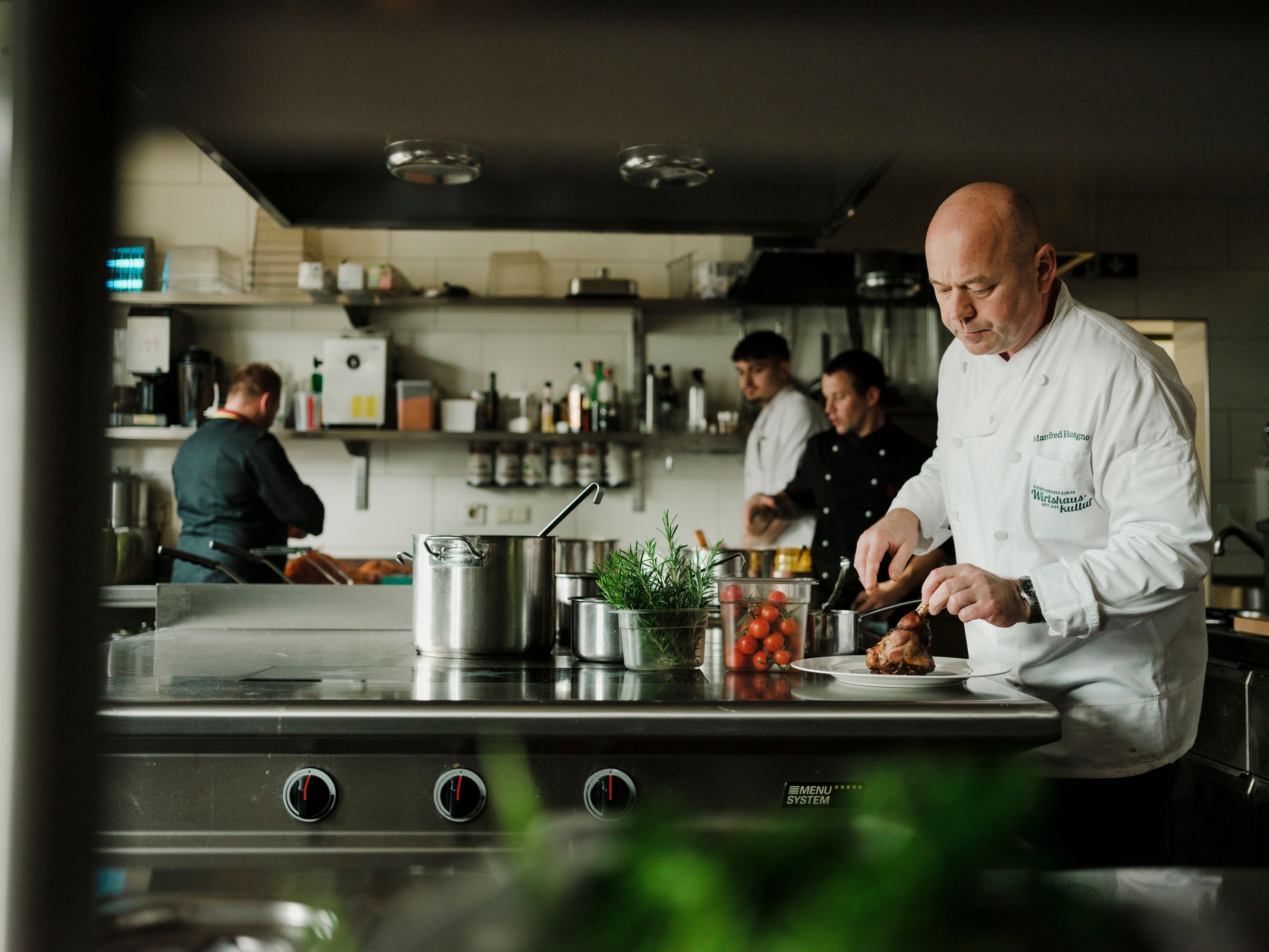 Köche arbeiten in einer professionellen Küche, einer schneidet Fleisch.