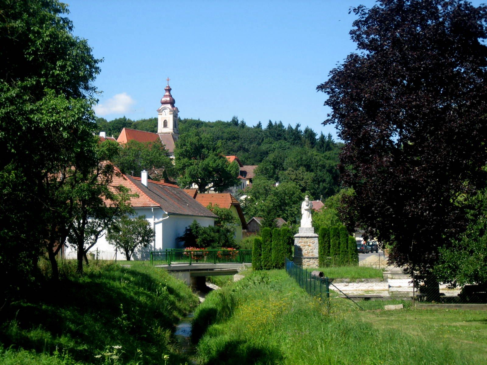 Krajina s kostelem a sochou ve vesnici.