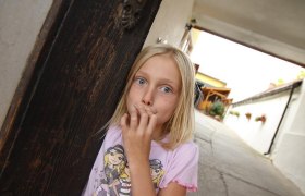 Ein Mädchen steht in einem Torbogen und schaut überrascht in die Kamera.