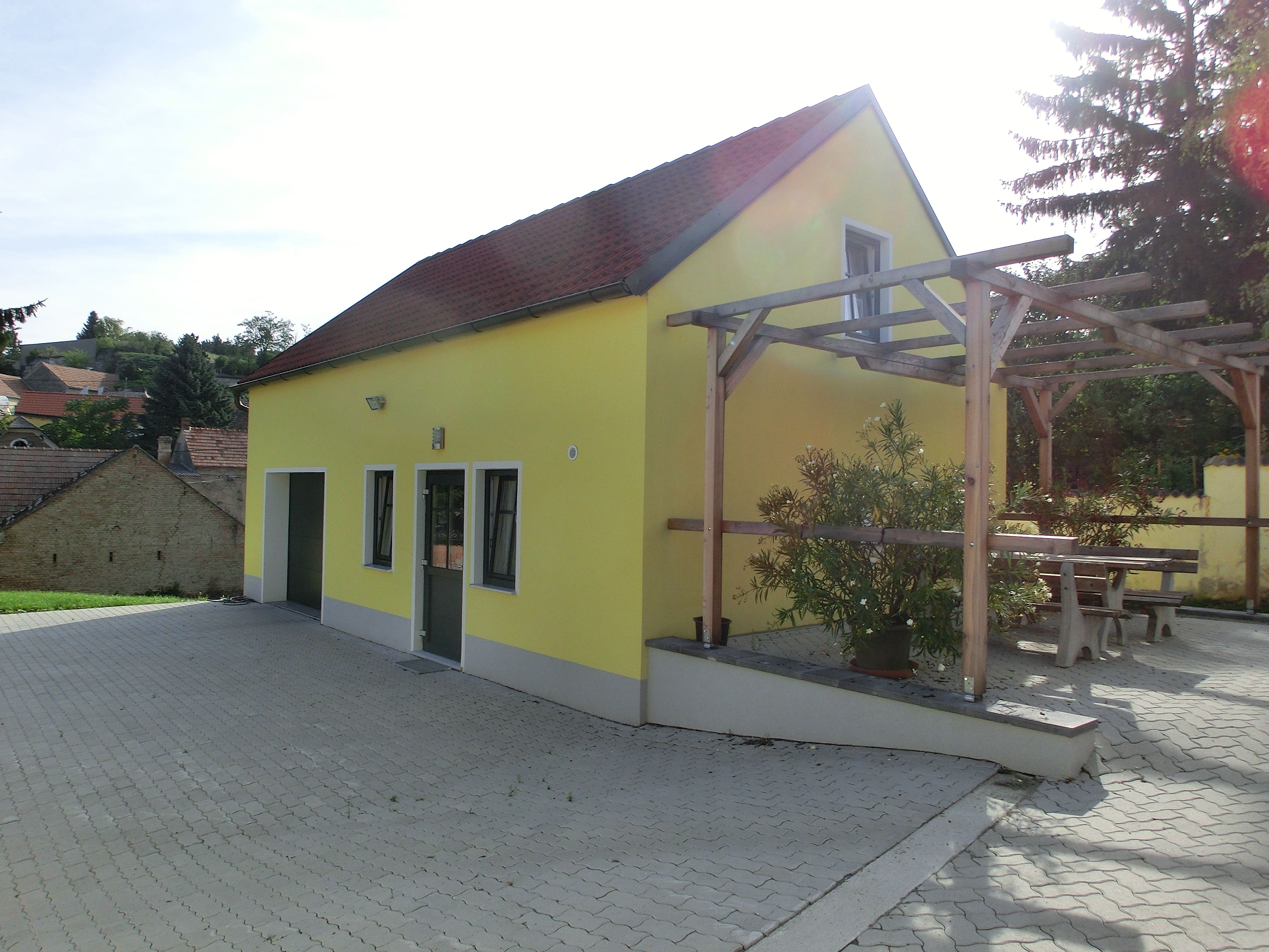 Gelbes Gebäude mit rotem Dach und Pergola im Freien.
