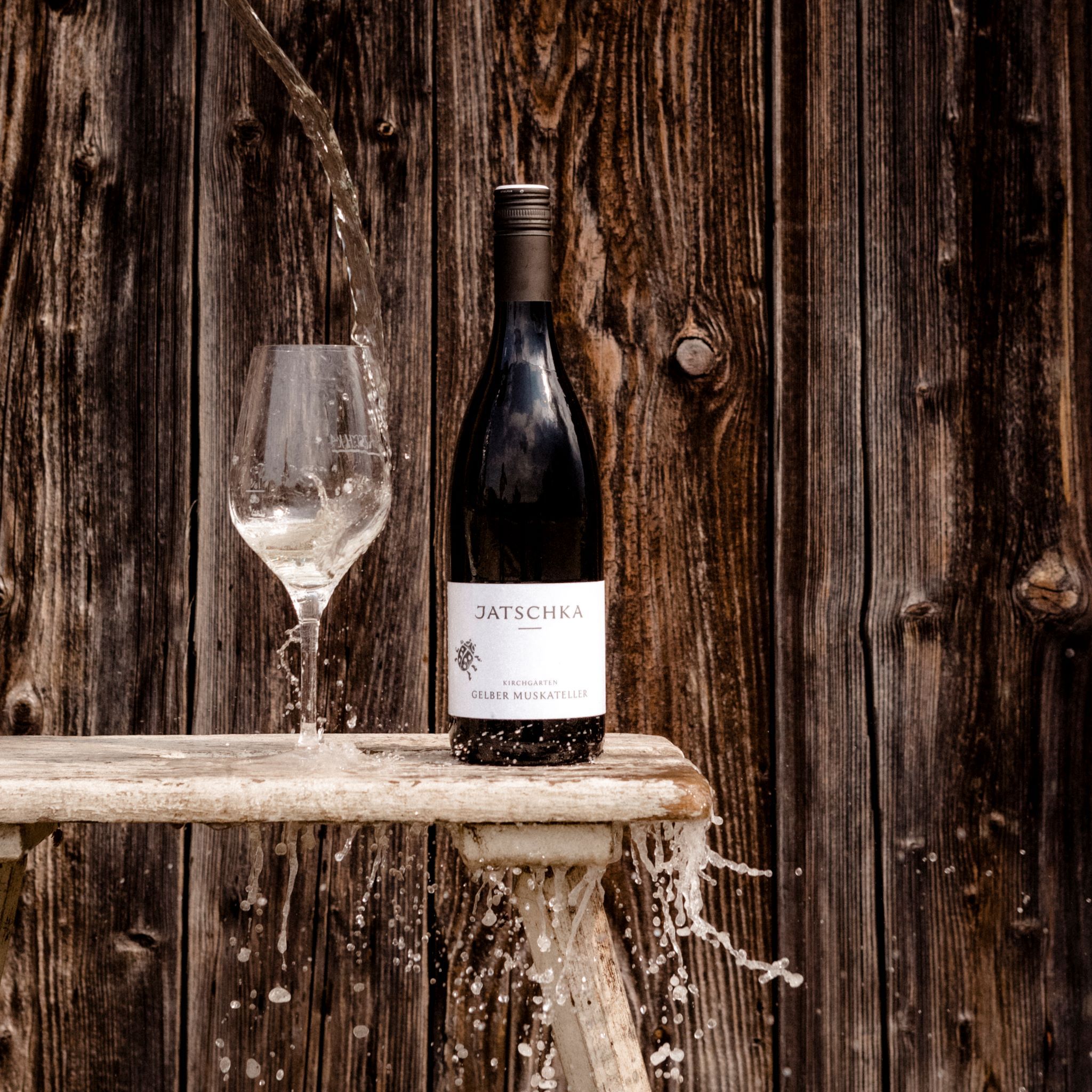 Fľaša vína a pohár vody pred drevenou stenou.