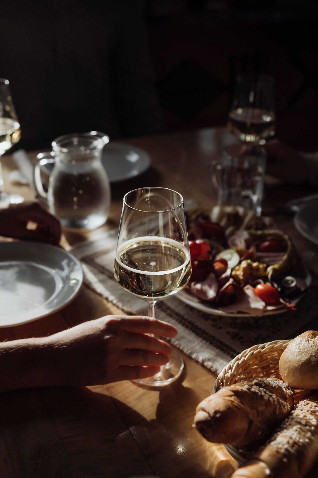 Genießen Sie einen entspannten Abend inmitten der Weinviertler Heurigenkultur, wo ein Glas erfrischender Weißwein auf dem Tisch steht. Die rustikale Brettljause, reich an regionalen Köstlichkeiten, lädt dazu ein, die Aromen der Umgebung zu entdecken und die gesellige Atmosphäre zu genießen.