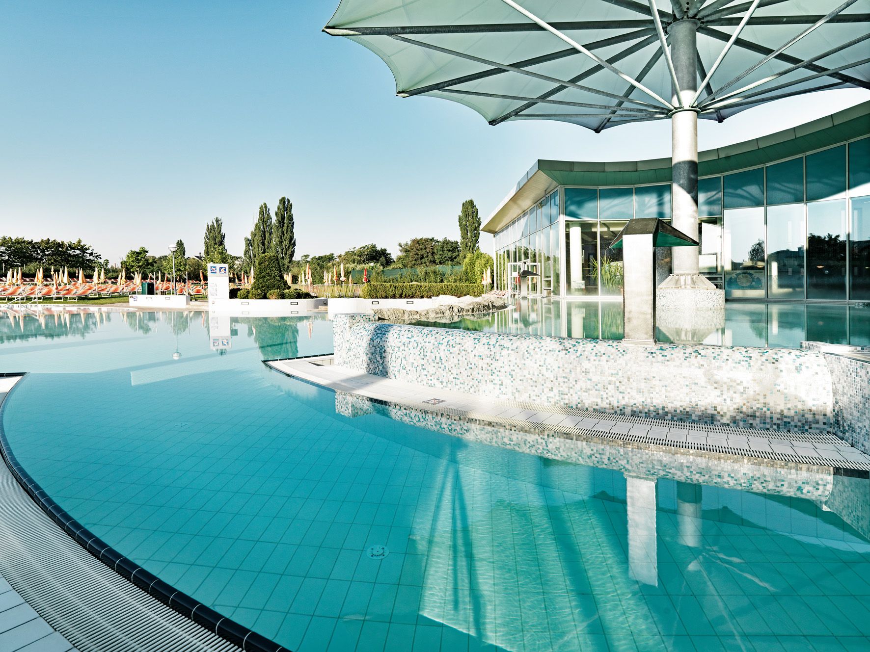 Außenbereich der Therme Laa mit Pool und Sonnenschirmen.