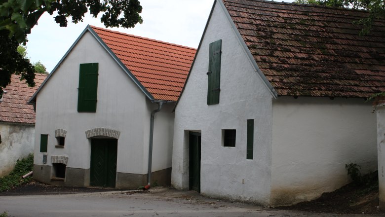Zwei traditionelle Weinkeller mit wei&szlig;en W&auml;nden und roten Ziegeld&auml;chern in einer Kellergasse.
