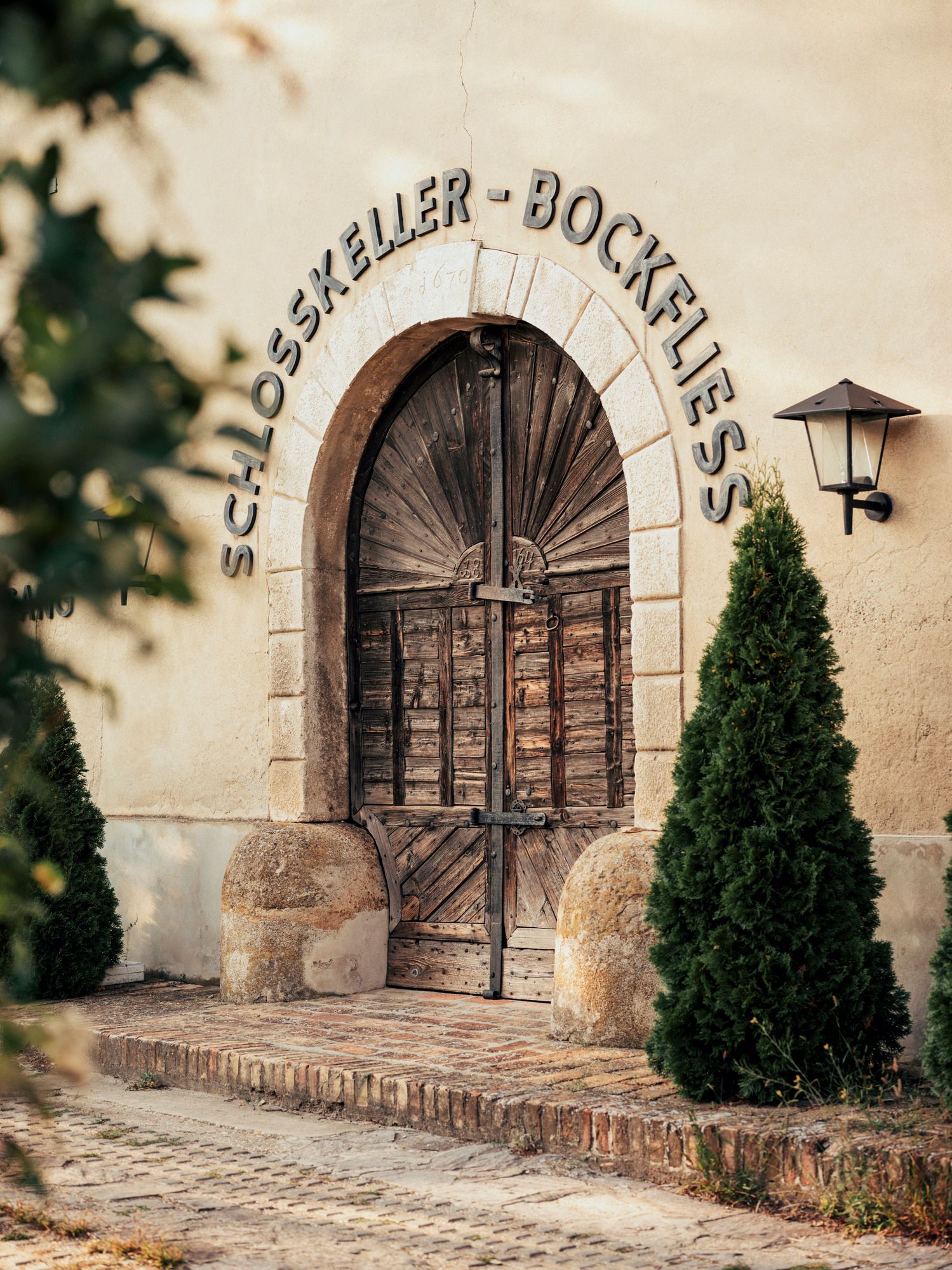 Eingang zum Schlosskeller mit Holztür und Schriftzug 'Schlosskeller - Bockfließ'.