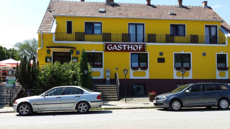 Gelbes Gebäude mit der Aufschrift 'Gasthof', zwei Autos davor geparkt.