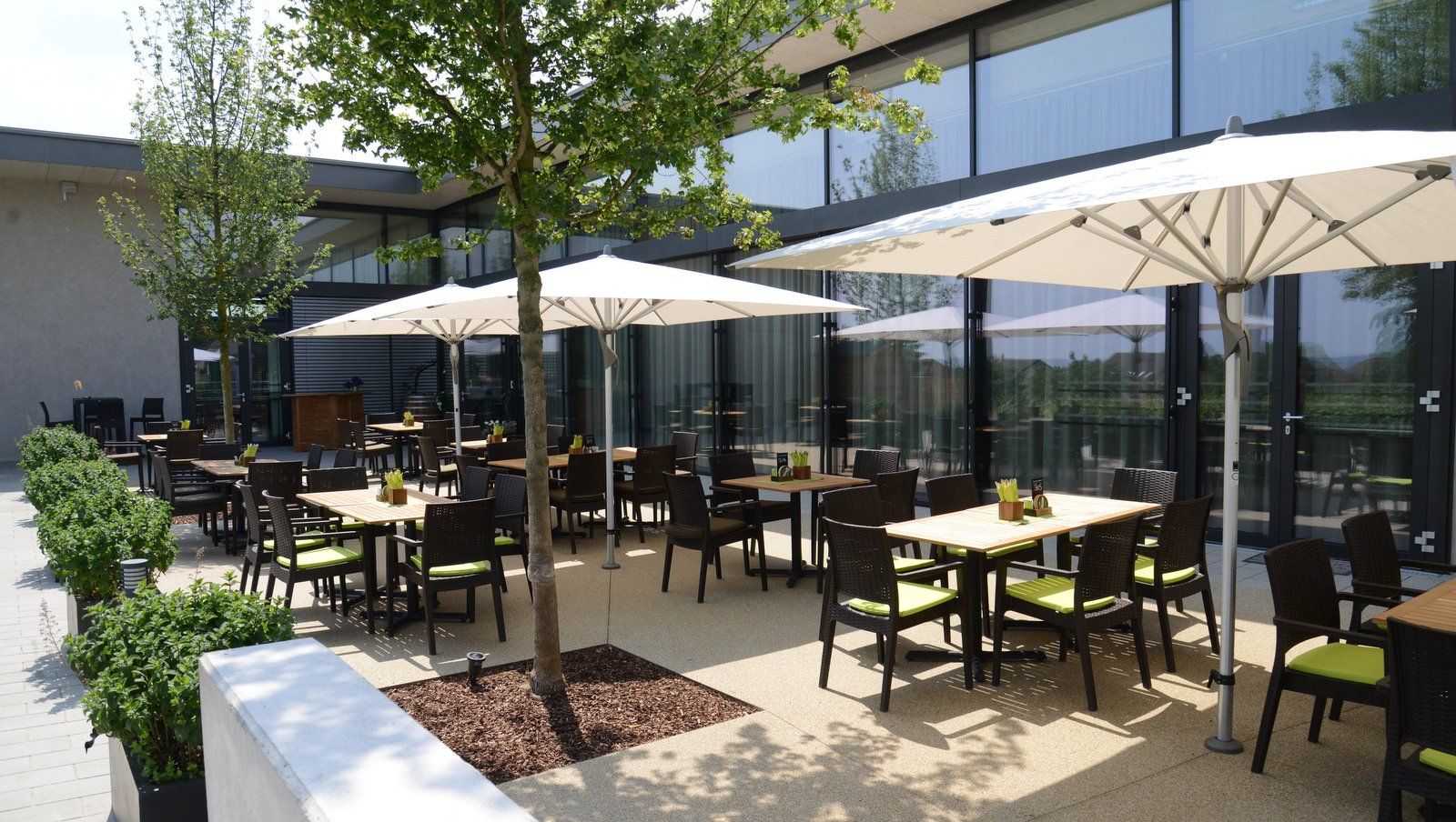 Terrasse eines Restaurants mit Tischen, Stühlen und Sonnenschirmen.