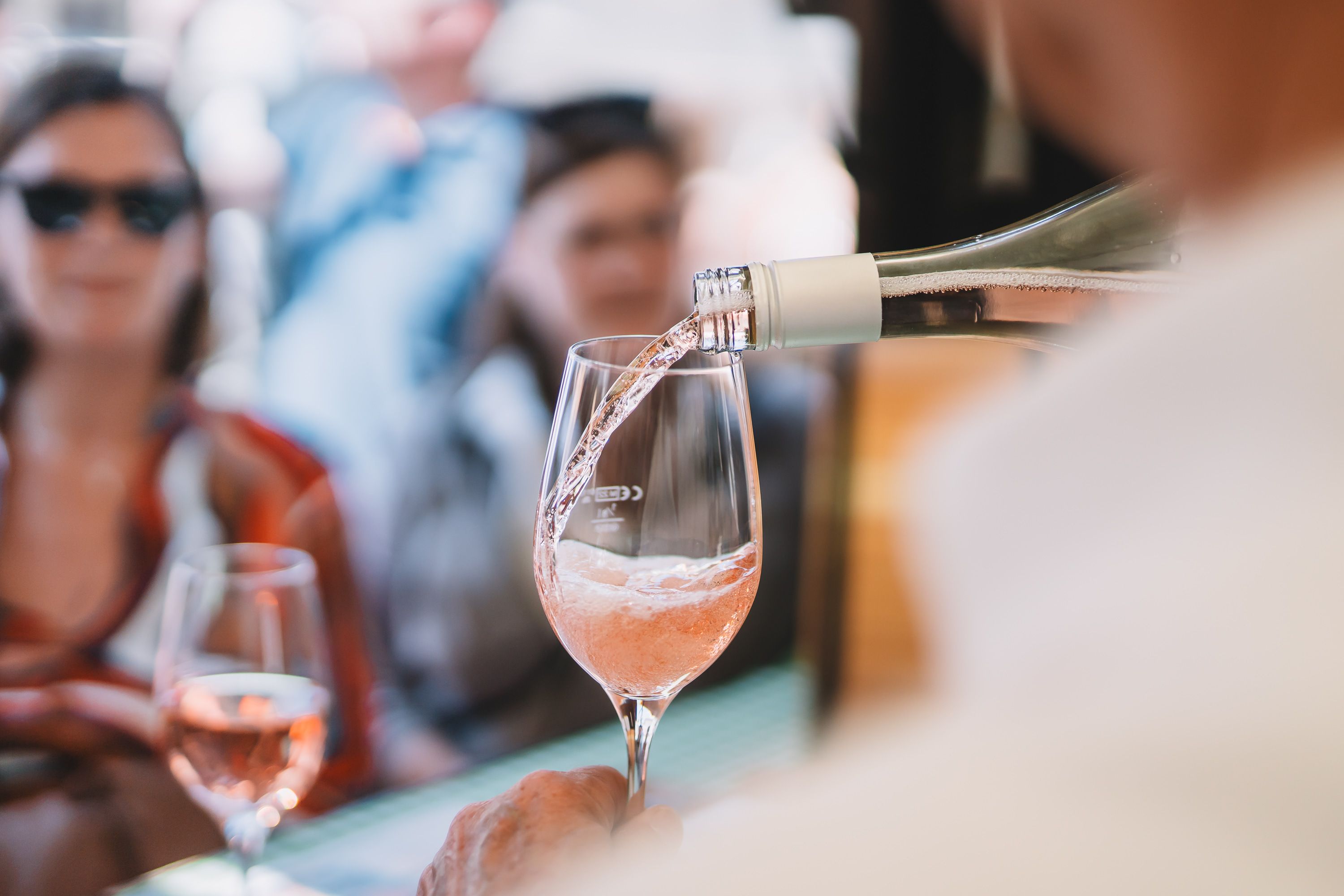 Einer Personengruppe wird sprudeliger Frizzante Rosé eingeschenkt. 
