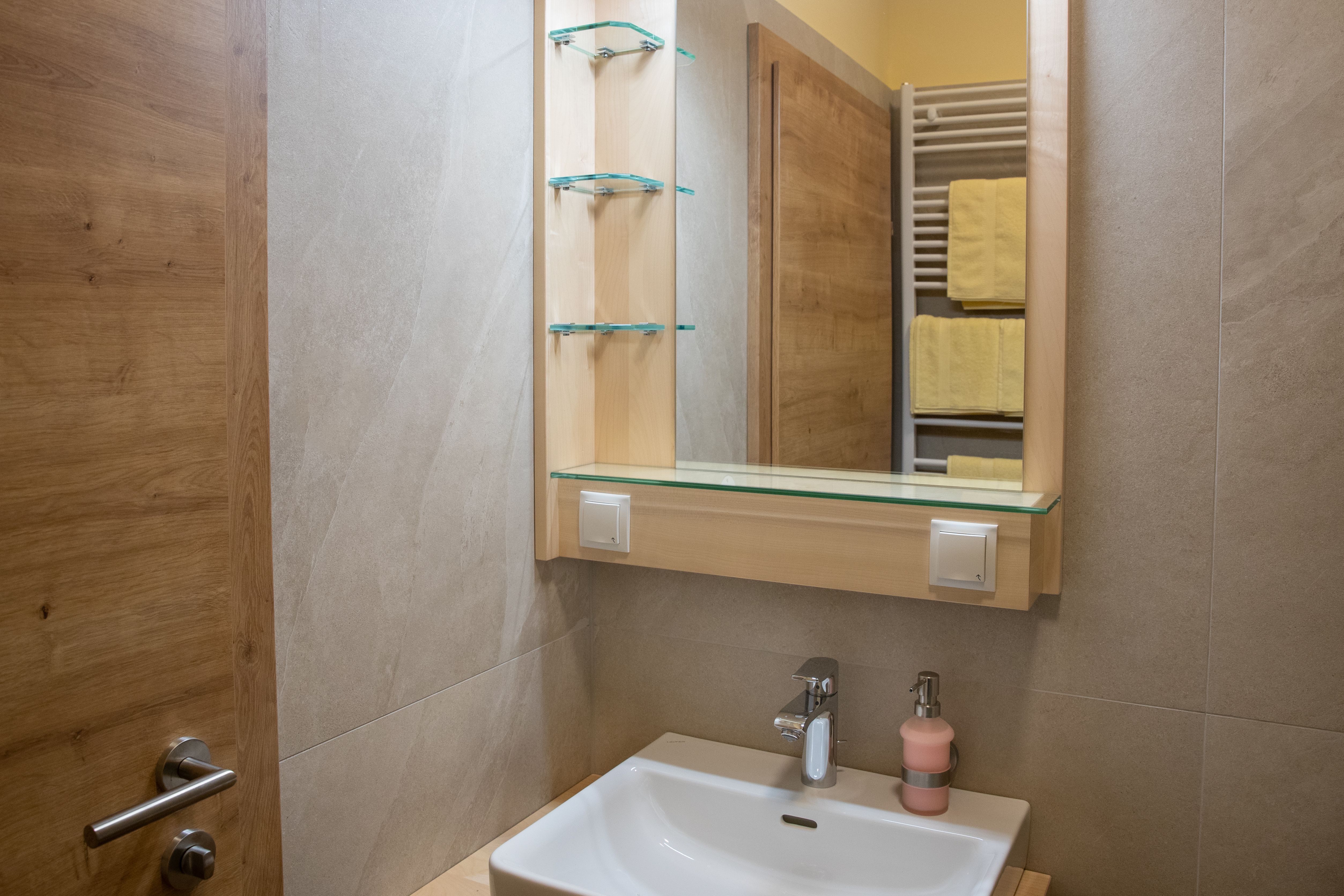 Modernes Badezimmer mit Waschbecken, Spiegel und Handtuchhalter.