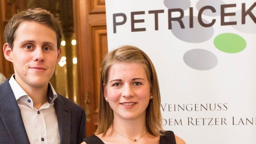 Two people in front of a banner with the inscription 'PETRICEK'.