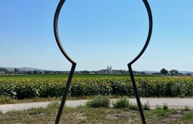 Metallrahmen in Form eines Schl&uuml;ssellochs mit Blick auf Wullersdorf und Sonnenblumenfeld.