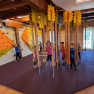 Kinder spielen in einem Indoor-Kletterraum mit Kletterwand und h&auml;ngenden Elementen.
