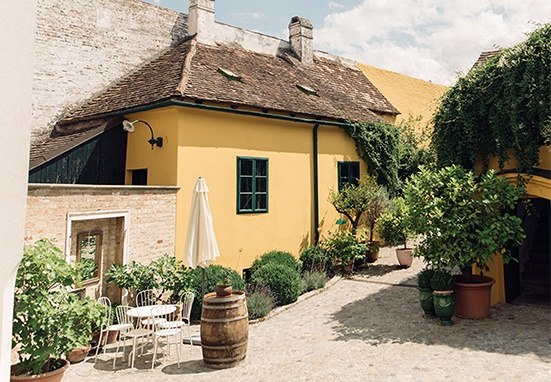 Ein malerischer Innenhof mit gelbem Haus, Pflanzen und Sitzbereich.