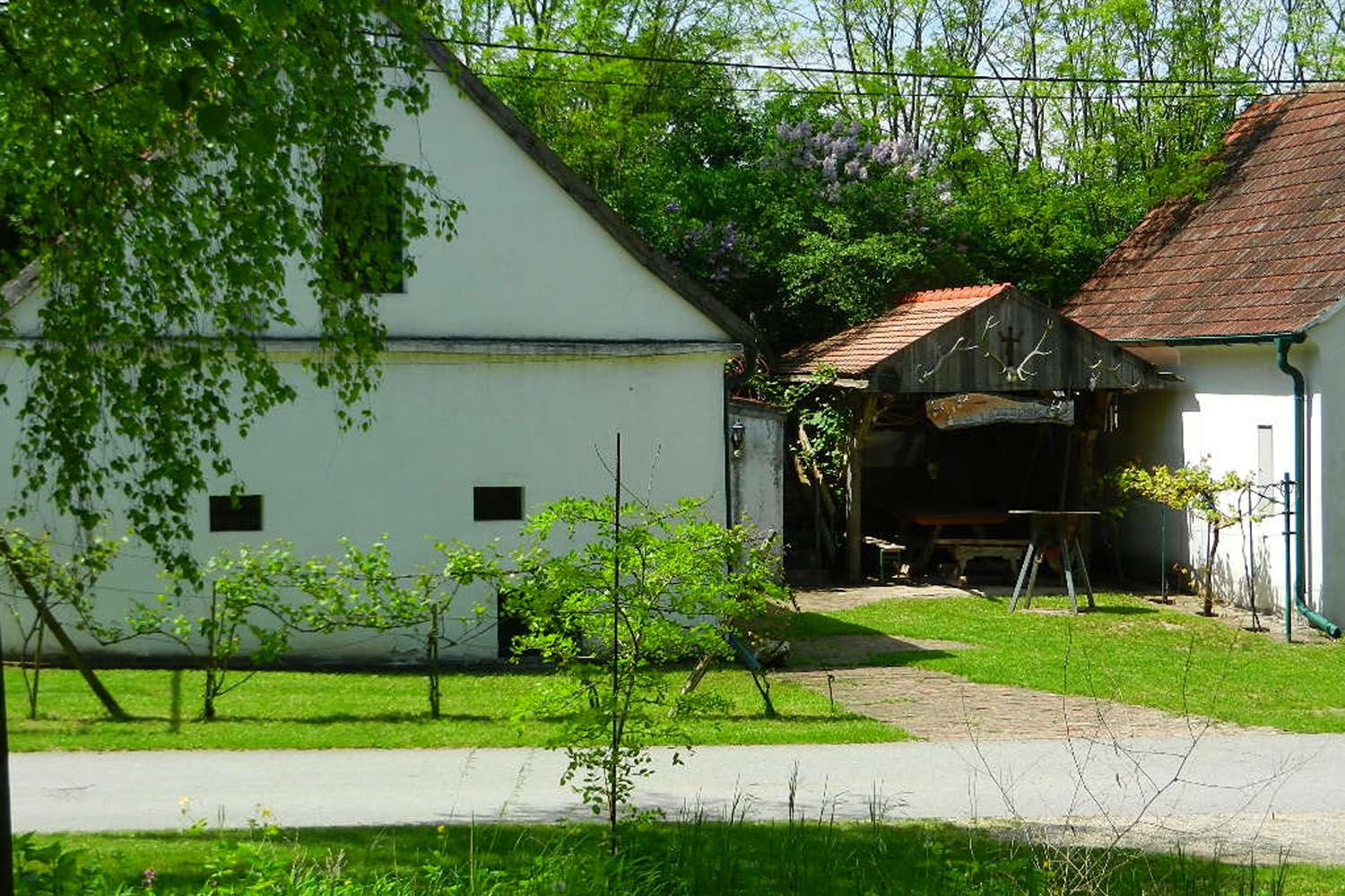 Ein ländlicher Hof mit weißen Gebäuden und grünem Garten.