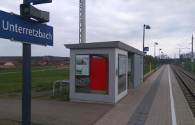 Kleiner Bahnhof Unterretzbach mit Wartehäuschen und Bahngleisen.