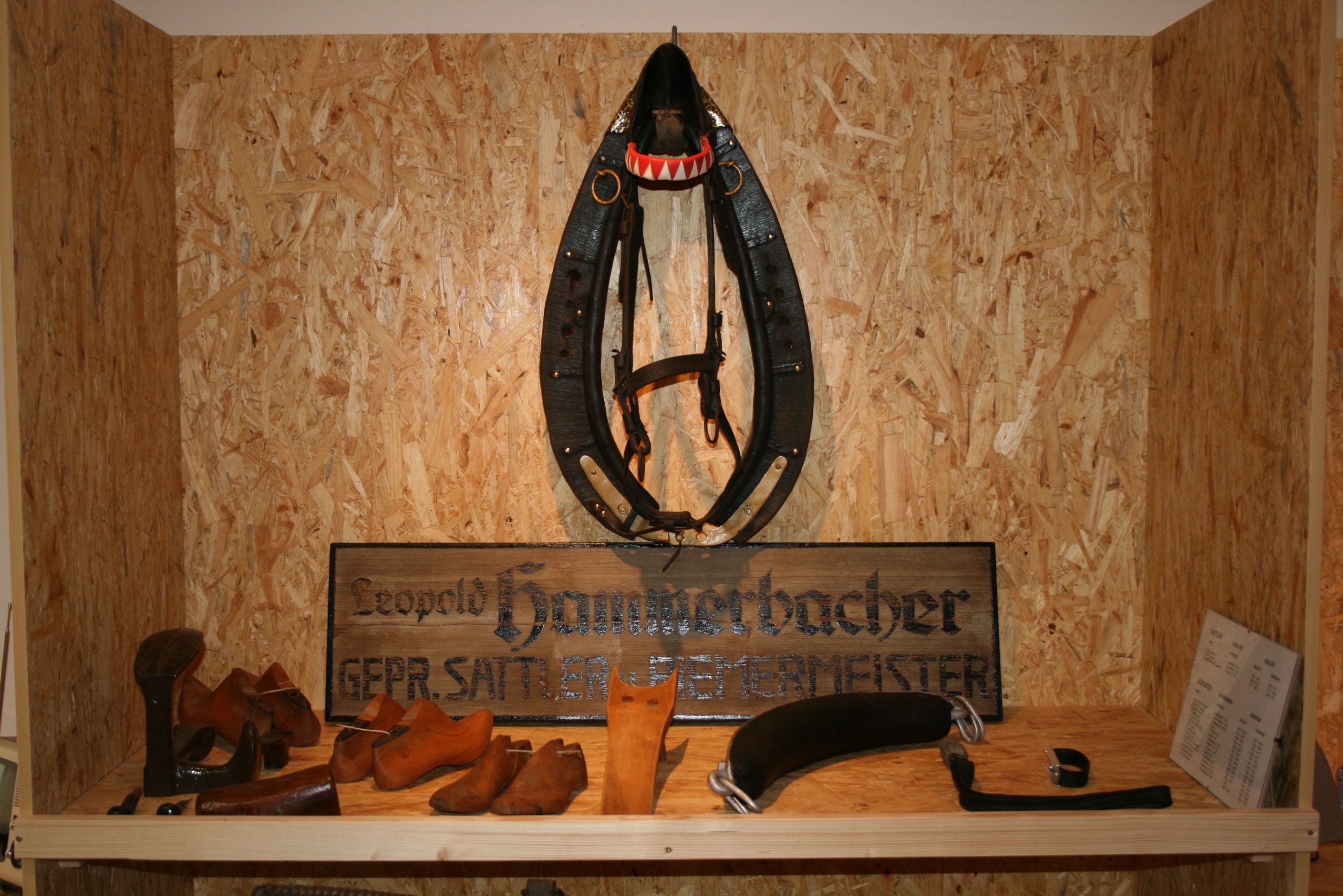 Ausstellungsstück in einem Museum mit Sattlerwerkzeugen und einem Pferdegeschirr.