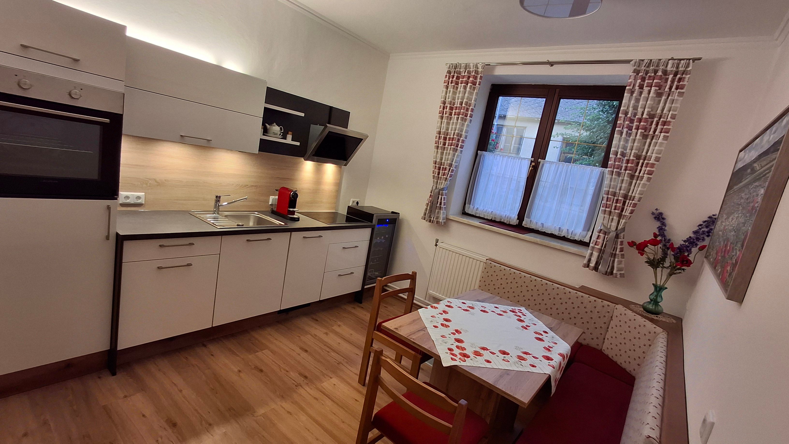 Moderne Küche mit Eckbank, Tisch und Fenster mit Vorhängen.