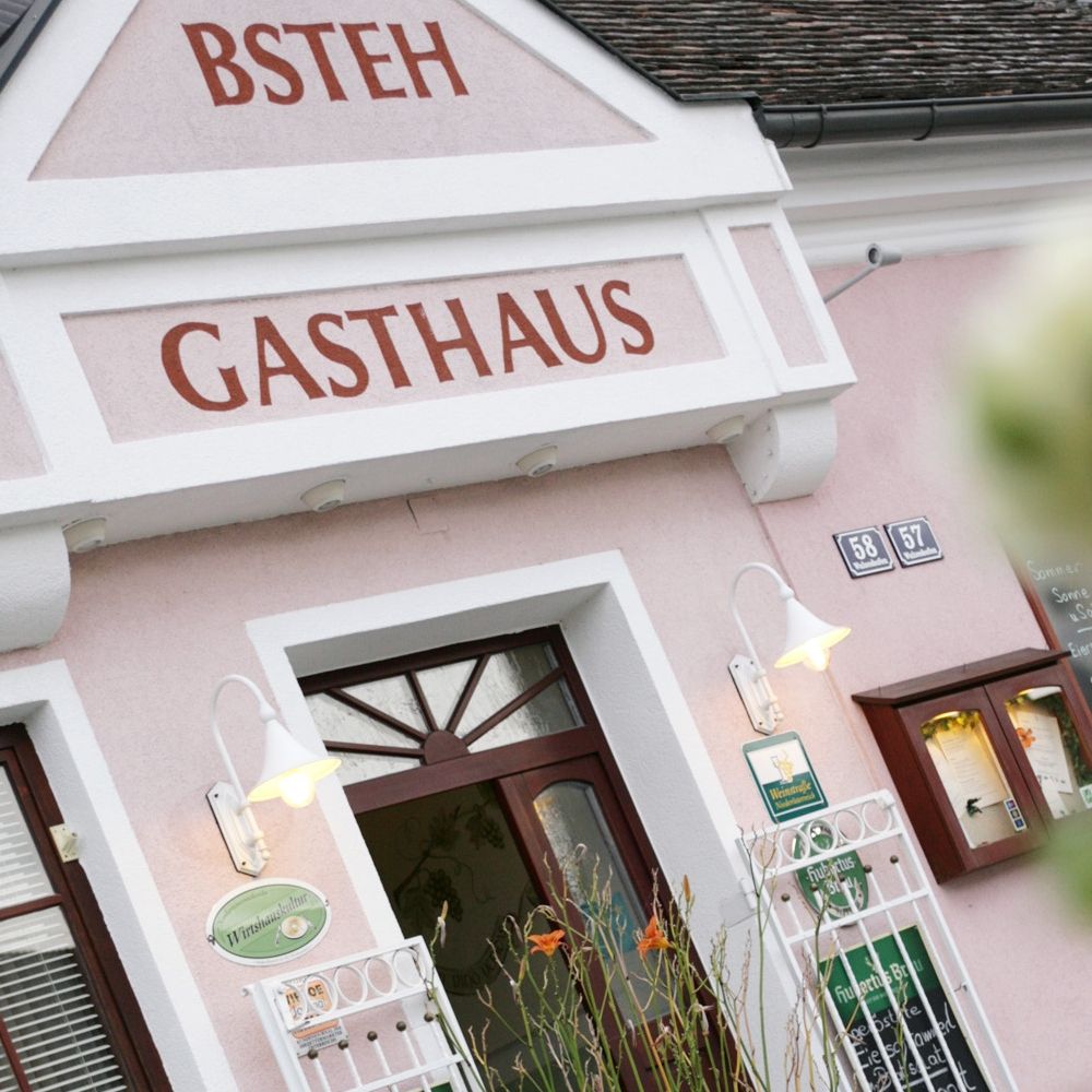 Eingang eines Gasthauses mit rosa Fassade und Beschilderung.