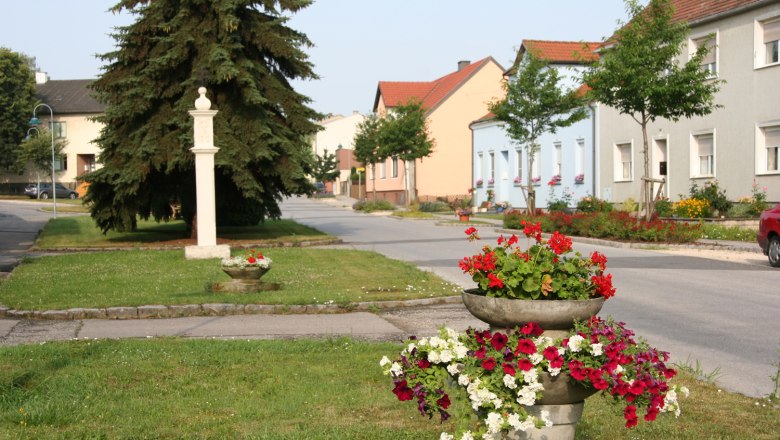 Straße in Sierndorf mit bunten Blumen und Häusern.