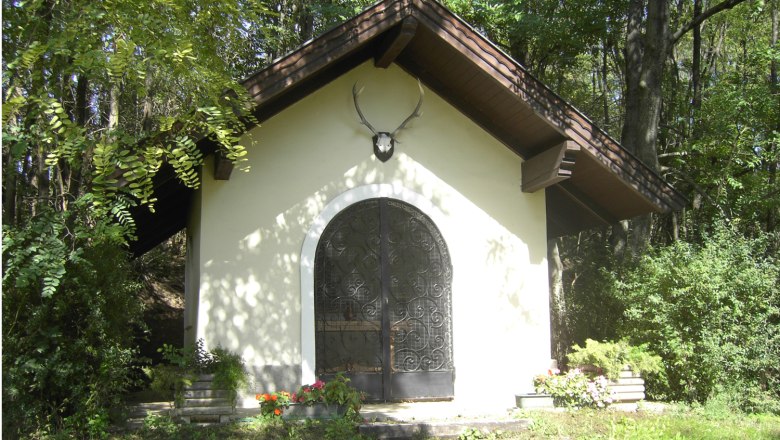 Eine kleine Kapelle im Wald mit einem Hirschgeweih über der Tür.
