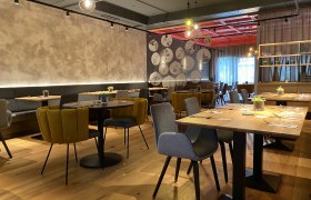 Modernes Restaurant mit stilvoller Einrichtung, Holztischen und gem&uuml;tlichen St&uuml;hlen.