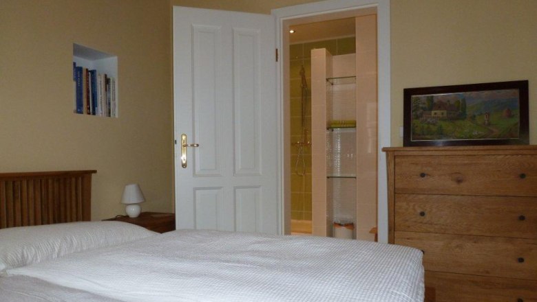 Doppelzimmer, © Wolfgang Pollak Ein gemütliches Doppelzimmer mit Bett, Kommode, Bücherregal und offenem Bad.