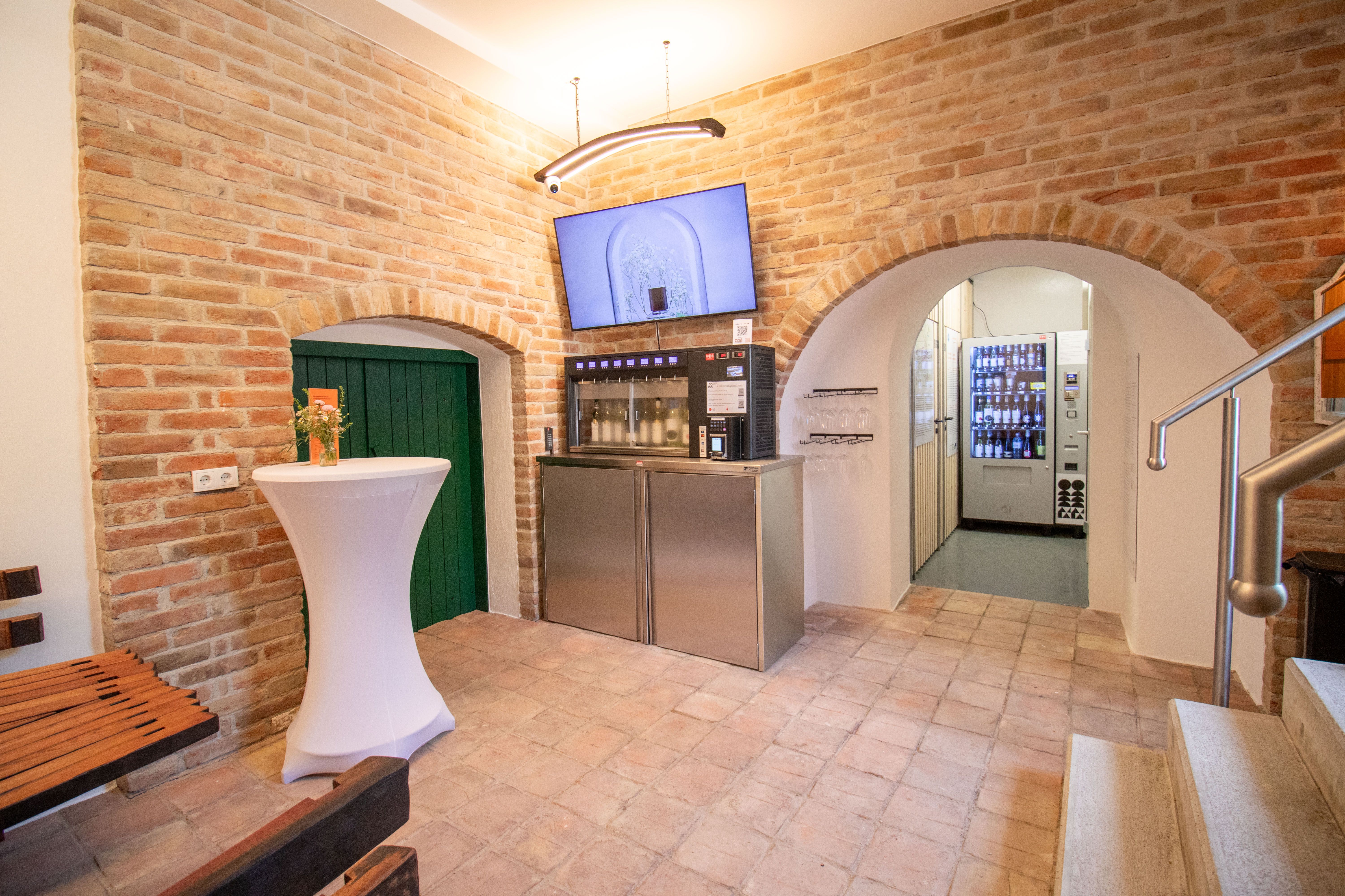 Interior view of a tasting room with brick walls, a tasting machine and a bar table.