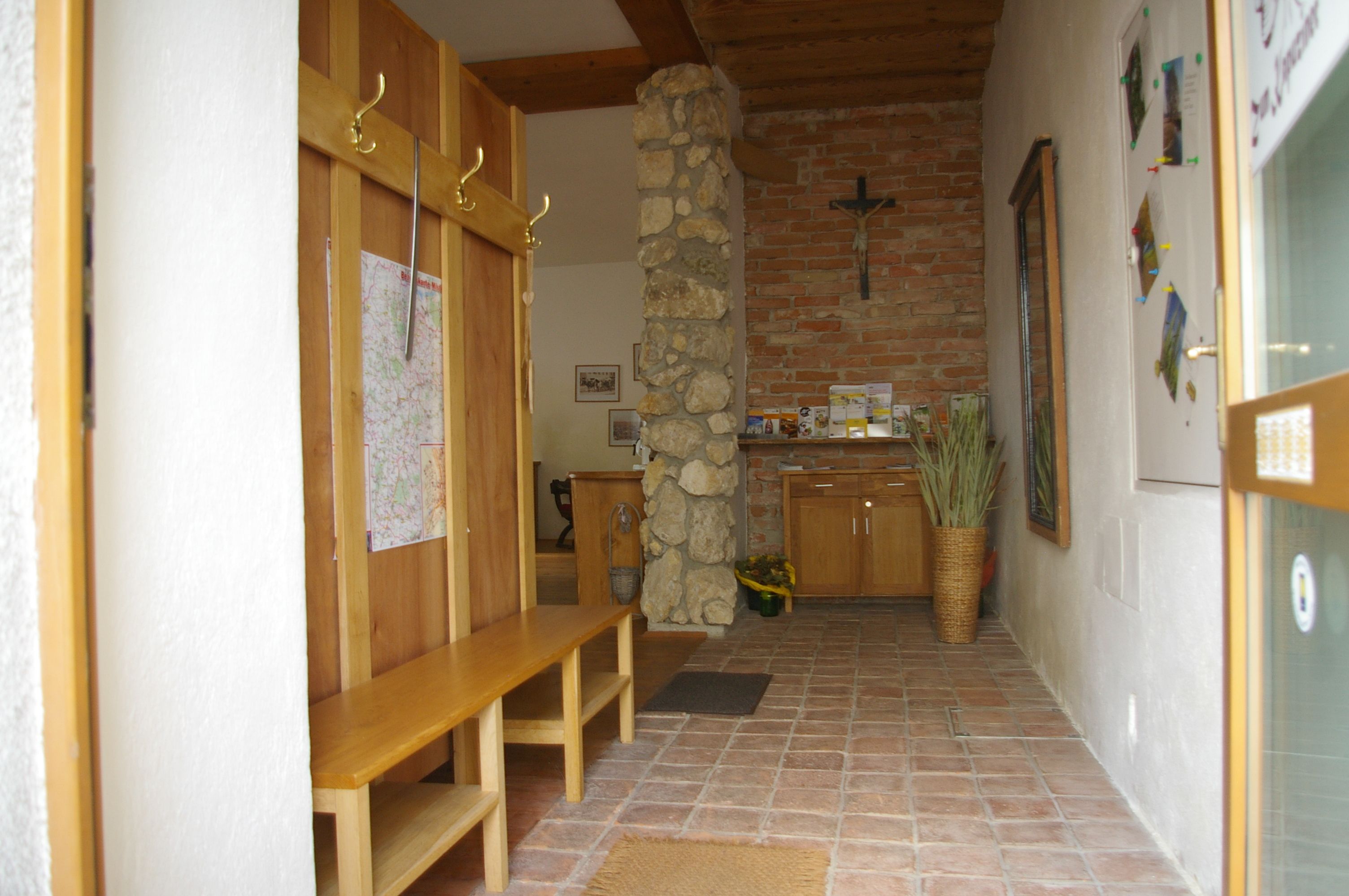 Entrance area with wooden benches, stone wall and cross.