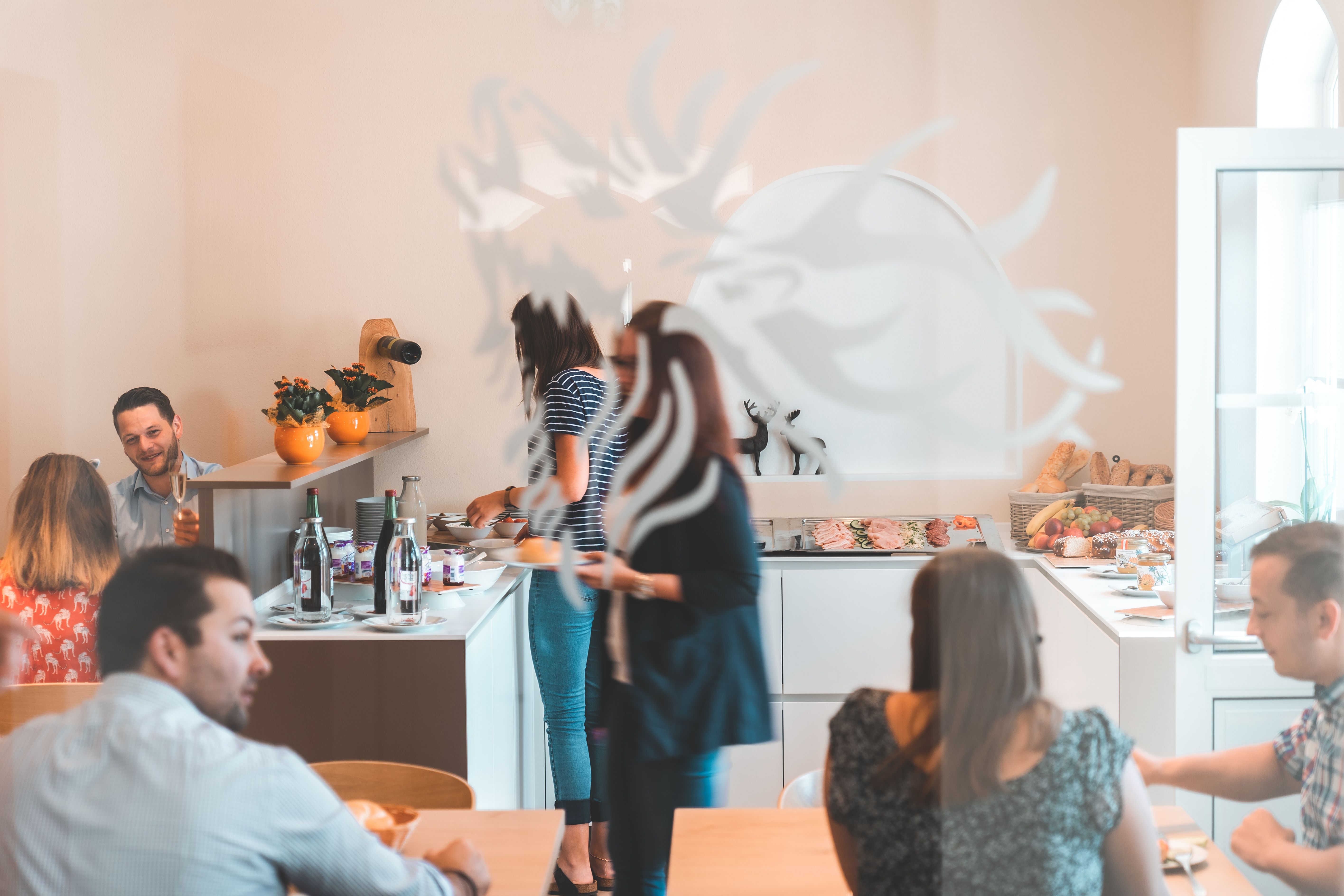 People help themselves to a breakfast buffet in a bright room.