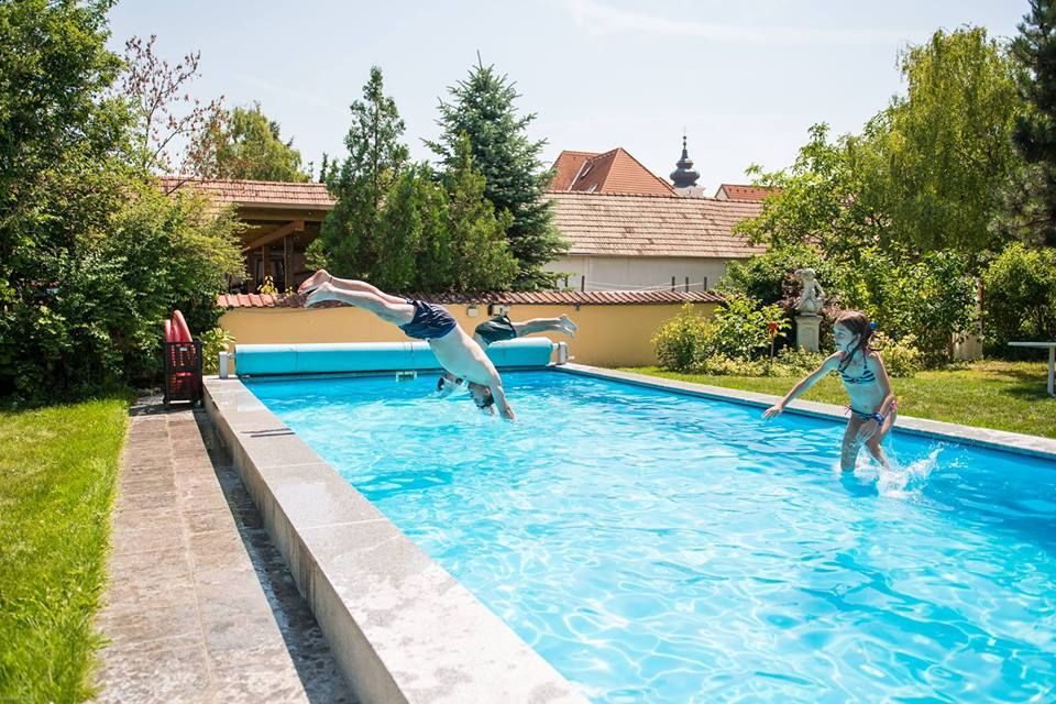 Kinder spielen in einem Swimmingpool auf einem Winzerhof.
