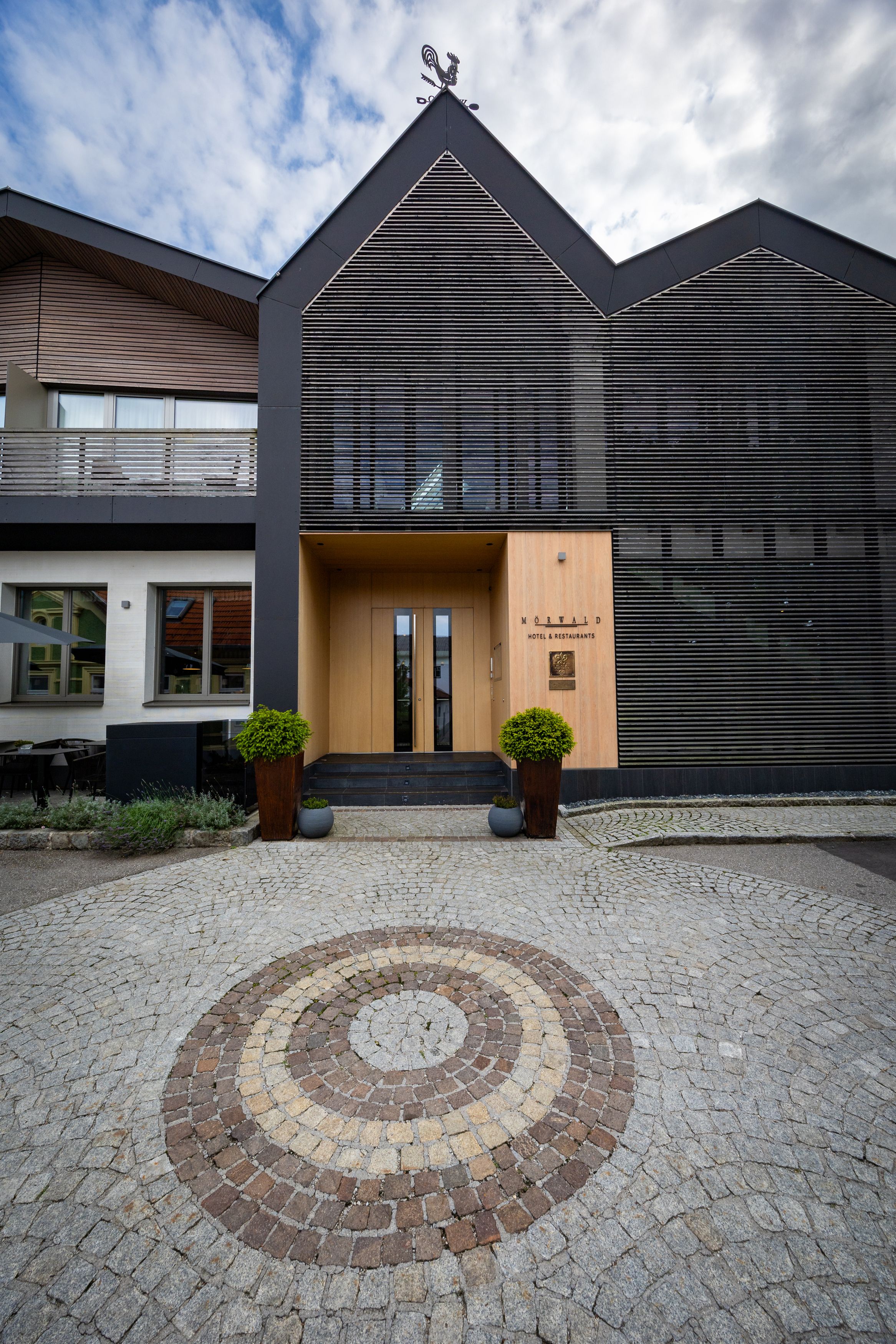 Eingang des Relais & Chateaux Mörwald Hotels mit moderner Architektur und gepflastertem Vorplatz.