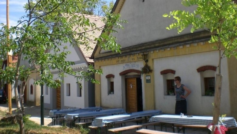 Traditional wine cellars with wooden doors and benches outside.