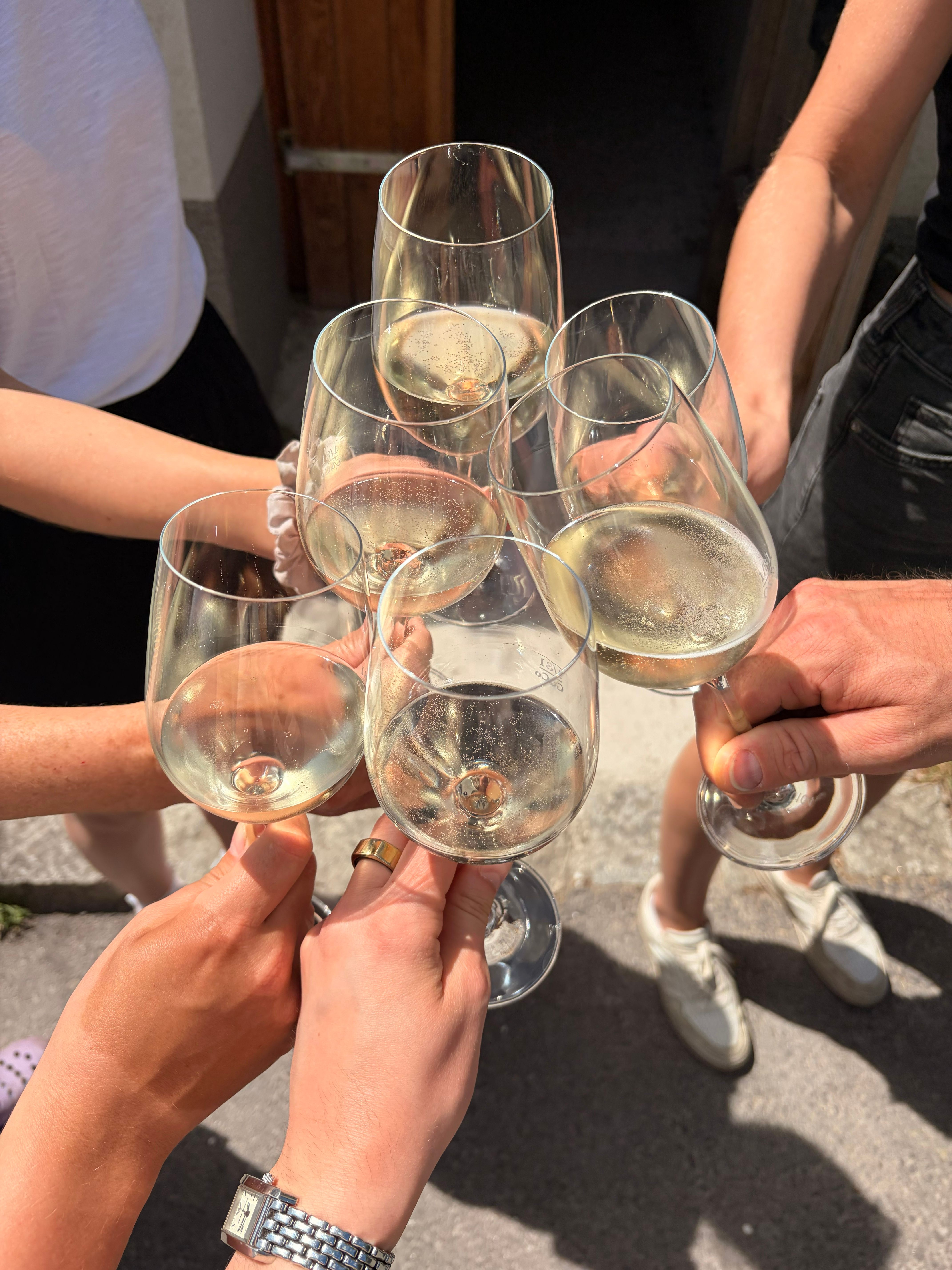 Mehrere Personen stoßen mit Gläsern Weißwein an der Trinkstation Weinbau Ackerl an.