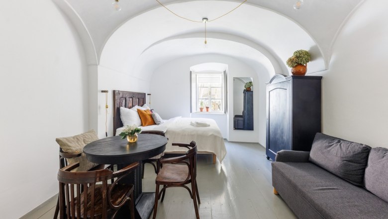 Guest room, © Fam. Sebök A stylishly furnished guest room with vaulted ceiling, bed, sofa, table and chairs. A window lets in natural light.