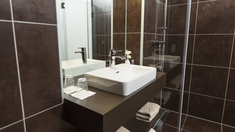 Modernes Badezimmer mit Waschbecken, Spiegel und Dusche.