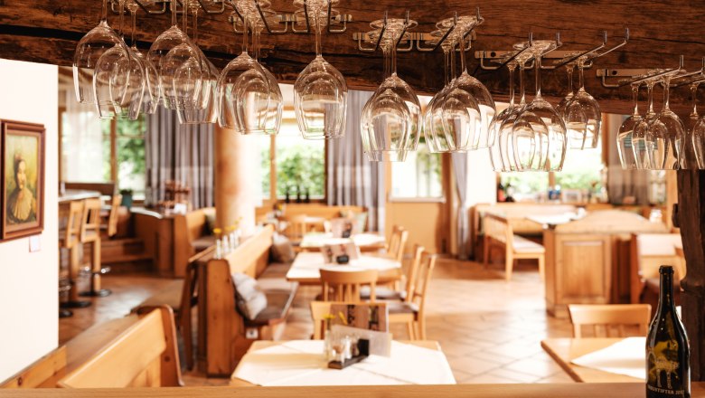 Interior view of a restaurant with hanging wine glasses and wooden furniture.