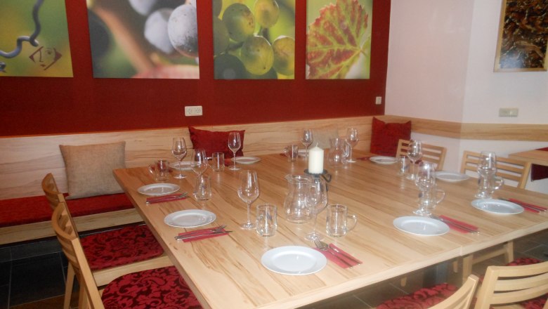 Ein Verkostungsraum mit gedecktem Holztisch, Weingläsern und Wandbildern von Weintrauben.