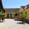 Inner courtyard of a yellow vineyard with cobblestones, swing and plants.