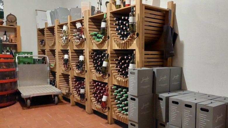 Weinkeller mit Regalen voller Weinflaschen und gestapelten Kartons.
