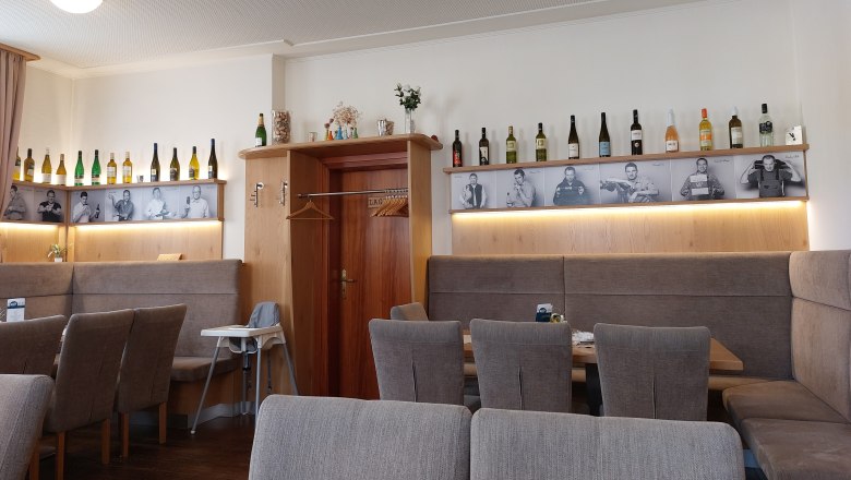 Innenansicht eines Restaurants mit Weinflaschen und Schwarz-Weiß-Fotos an der Wand.