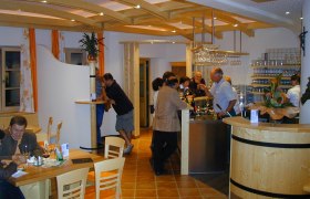 Innenansicht eines Heurigenlokals mit G&auml;sten an der Bar und an Tischen.