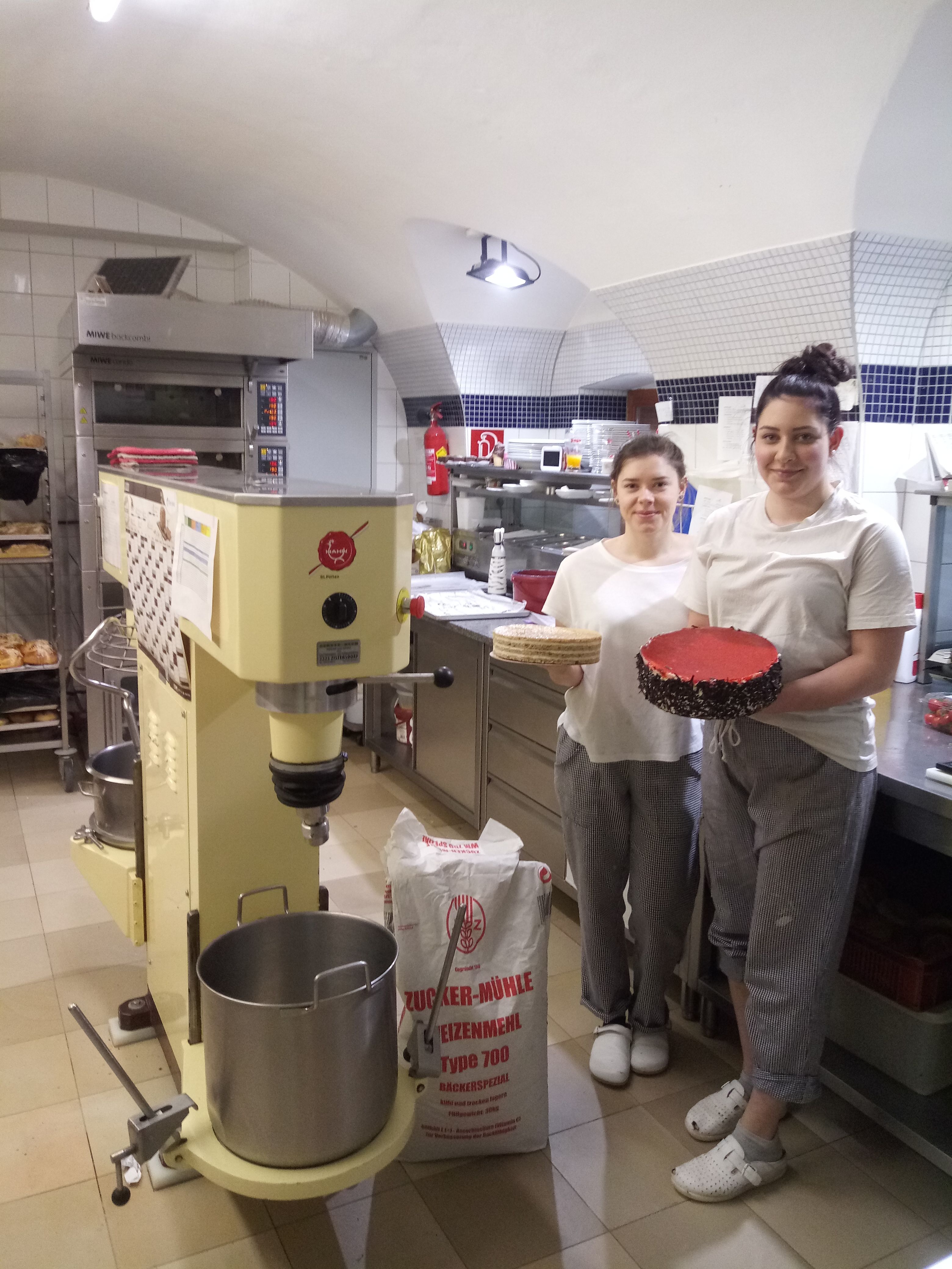 Zwei Personen in einer Backstube mit einer Torte und einem Kuchenboden.
