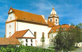 Wallfahrtskirche Maria Roggendorf mit rotem Dach und Turm vor blauem Himmel.