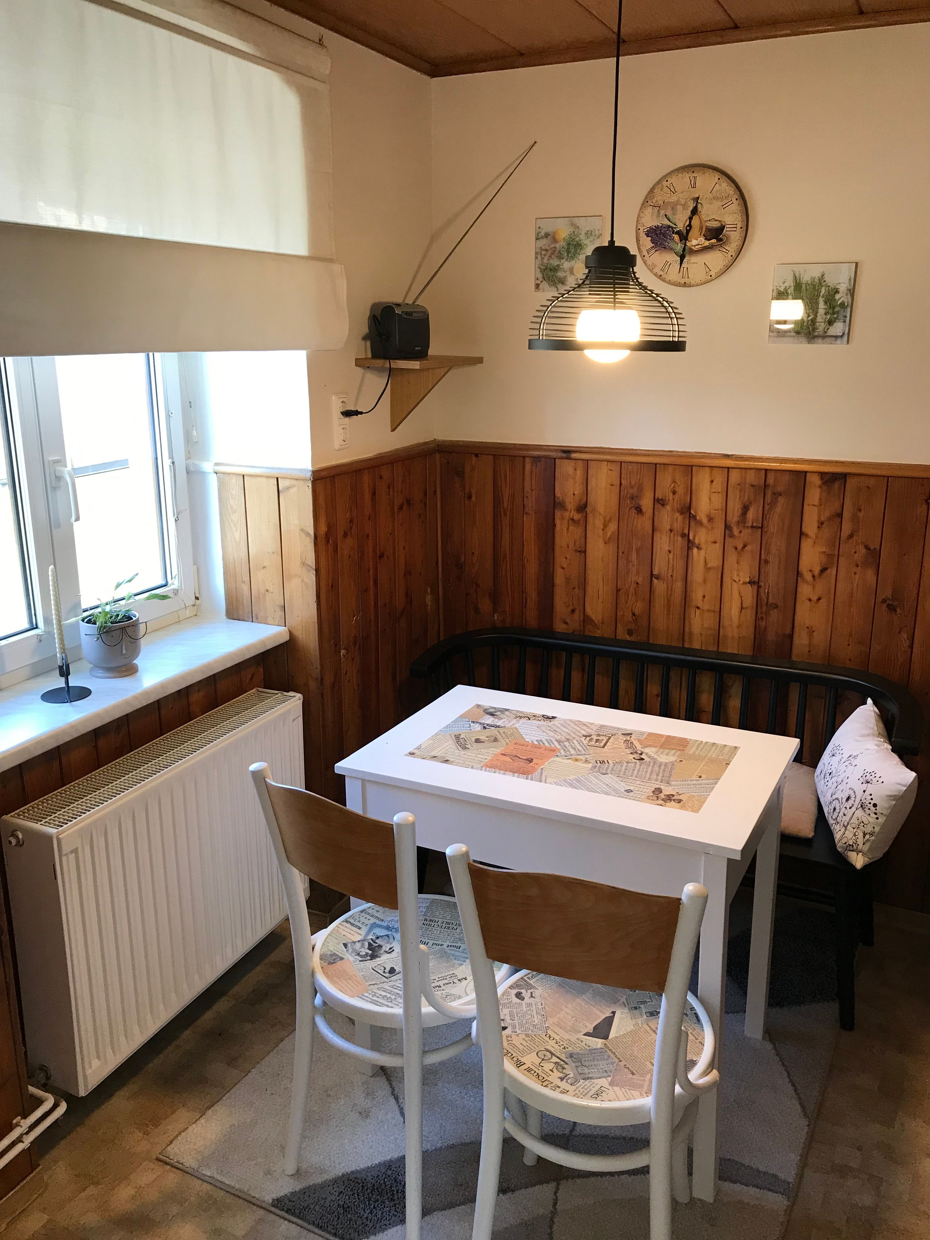 Kleine Essecke mit Tisch, Stühlen und Bank in einer Küche mit Holzvertäfelung.