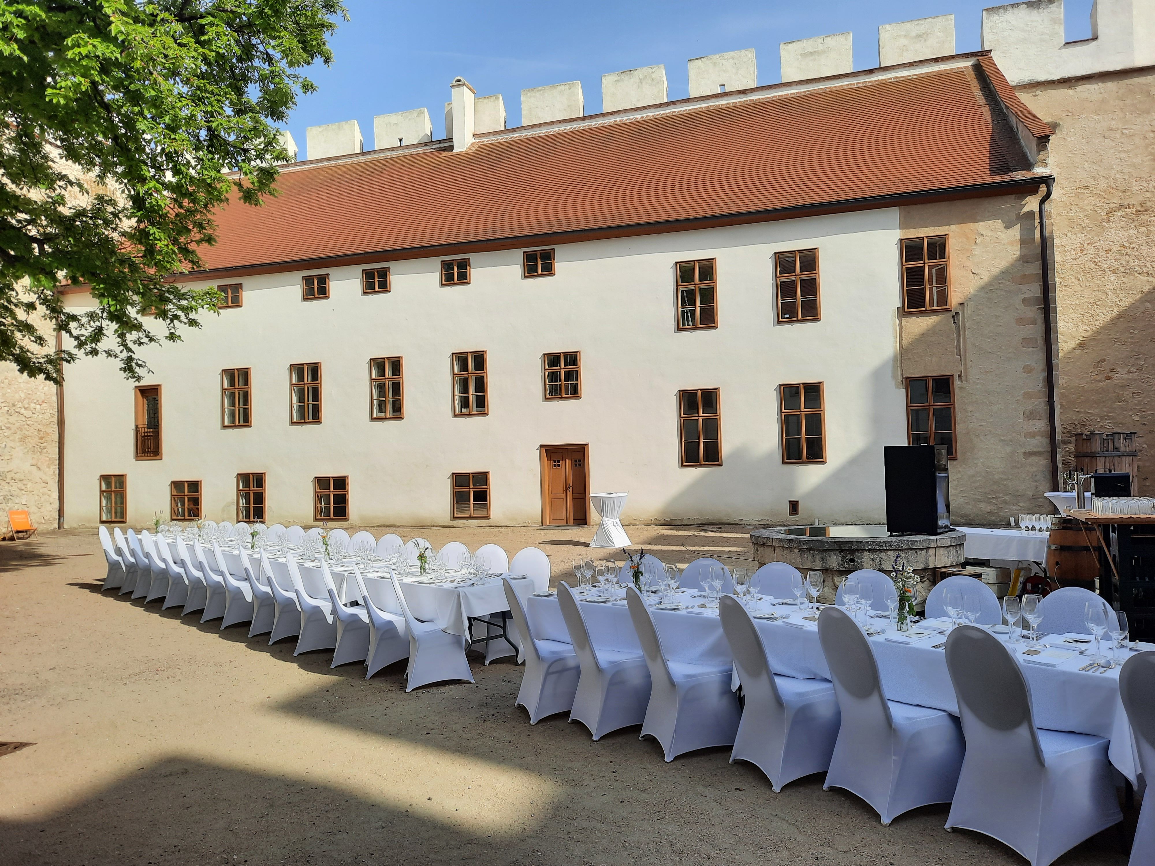 Langer, festlich gedeckter Tisch im Innenhof eines historischen Gebäudes.