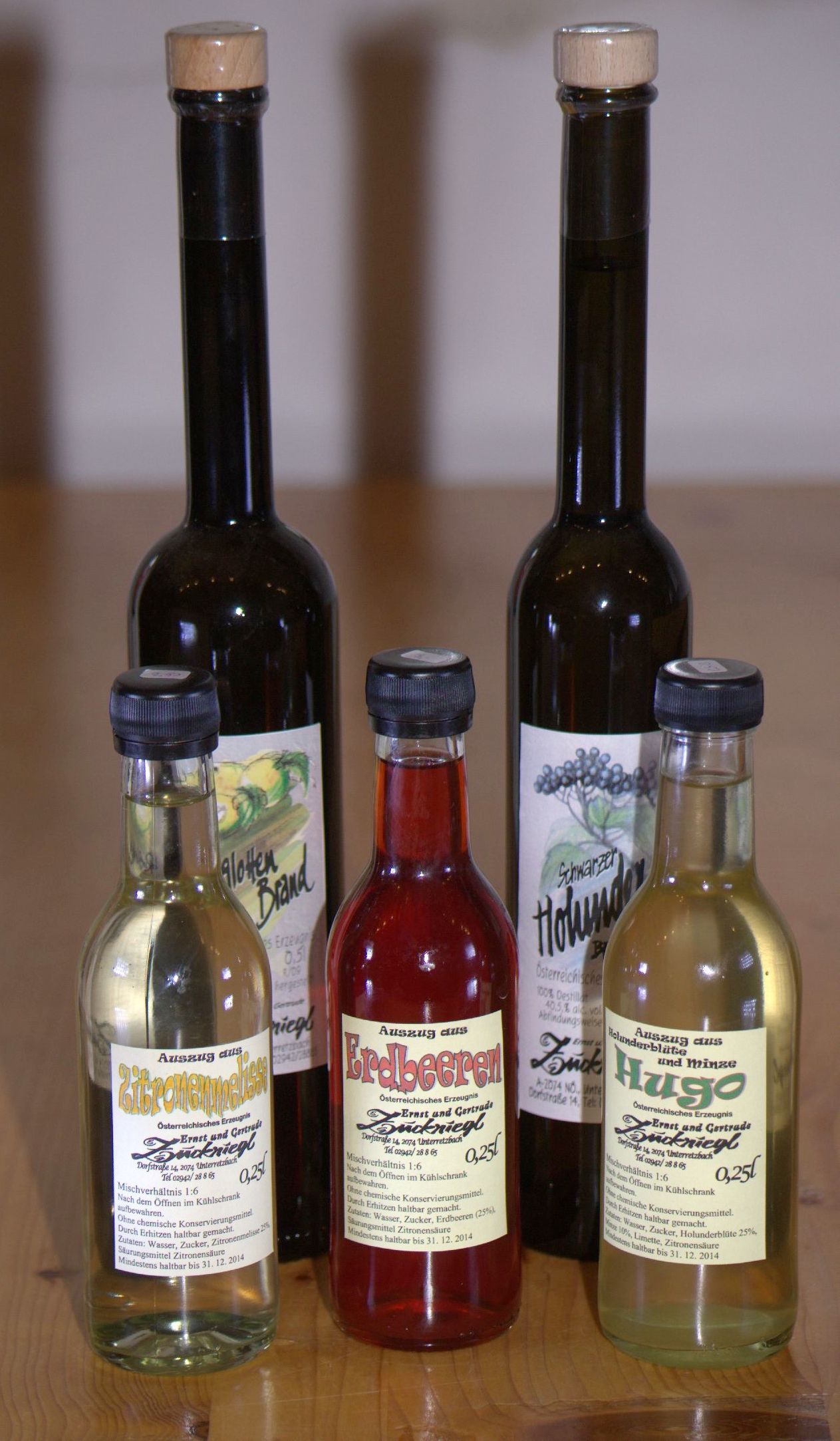 Five bottles of various syrups and schnapps on a wooden table.